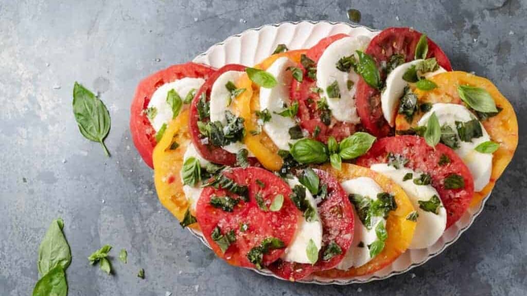 A plate with tomatoes and basil on it.