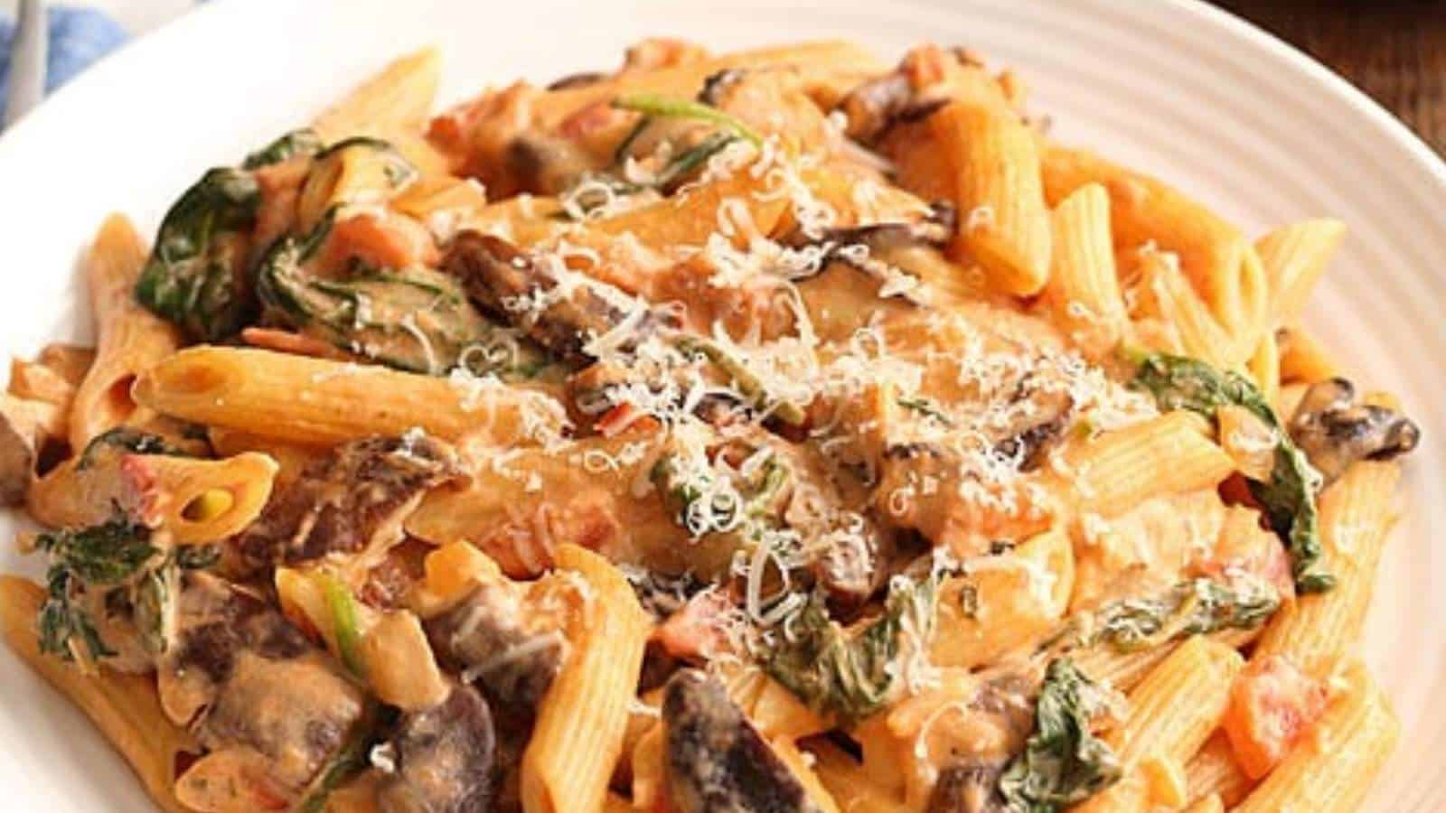 A plate of pasta with mushrooms and spinach.