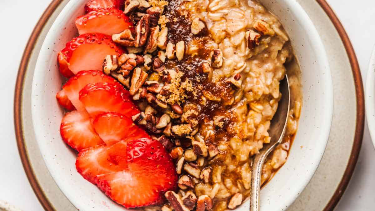 A bowl of oatmeal with strawberries and pecans.