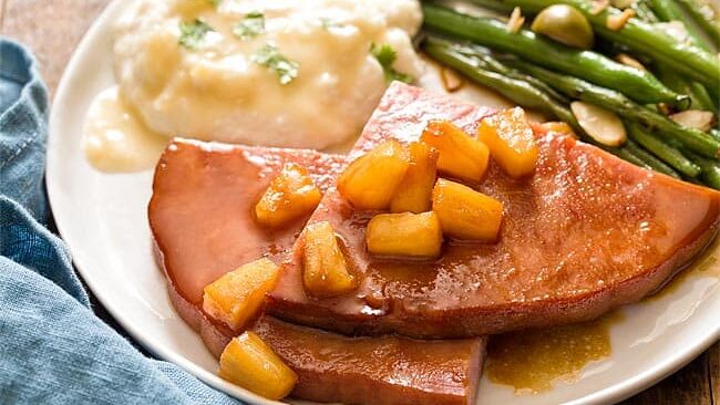 A plate with ham, green beans and mashed potatoes.