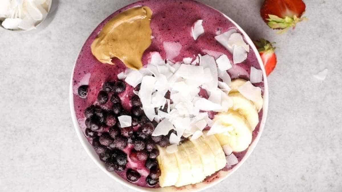 A bowl with blueberries, bananas, strawberries and peanut butter.