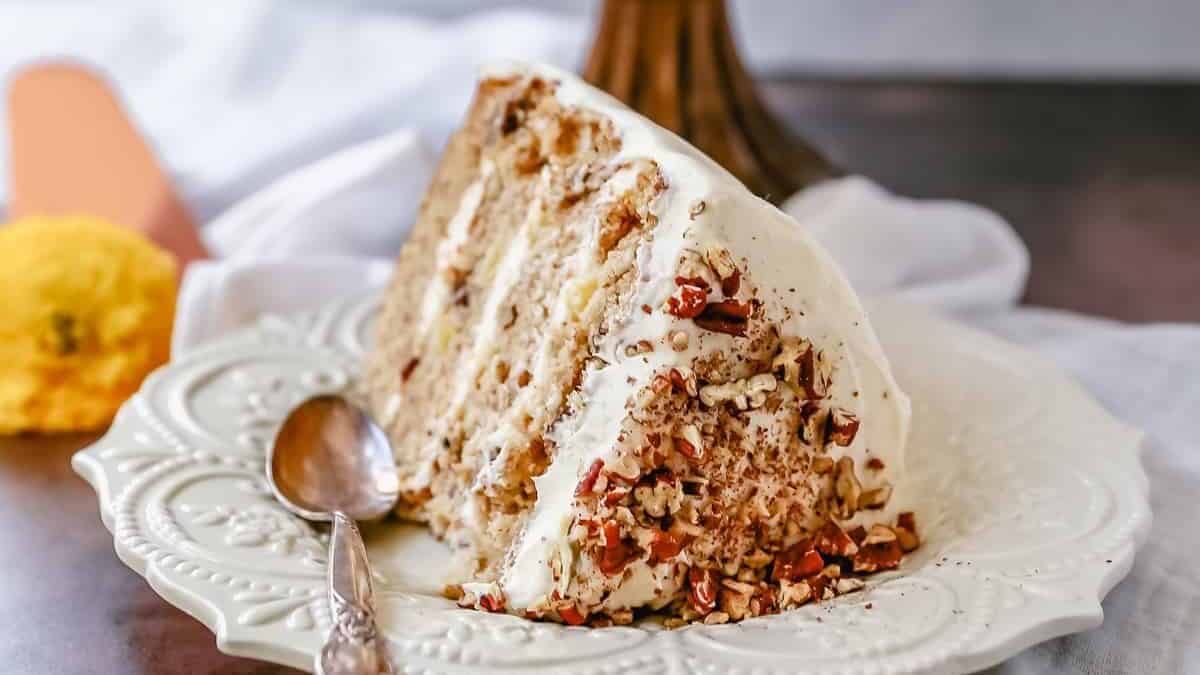 A slice of carrot cake on a plate with a spoon.