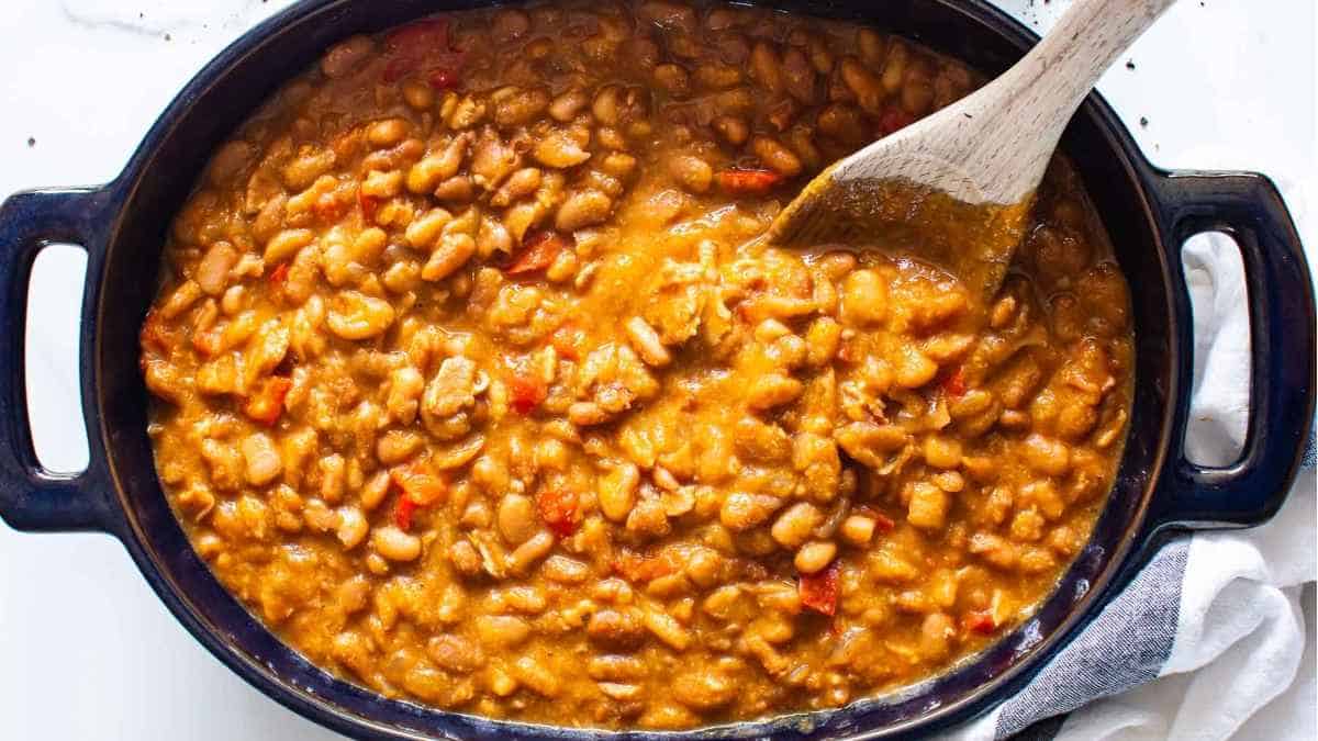 Beans in a pan with a wooden spoon.