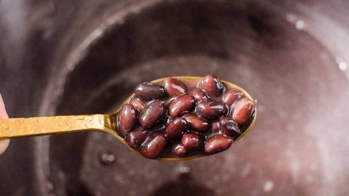 A spoon full of black beans in a pot.