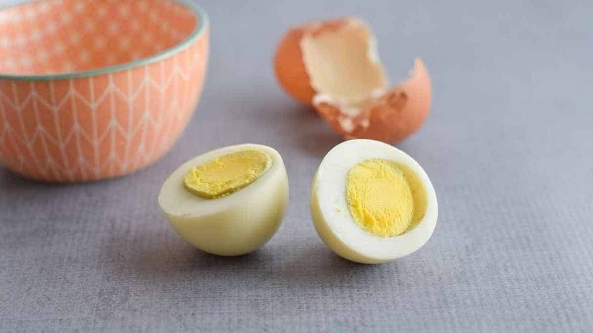 Two hard boiled eggs on a table next to a bowl.