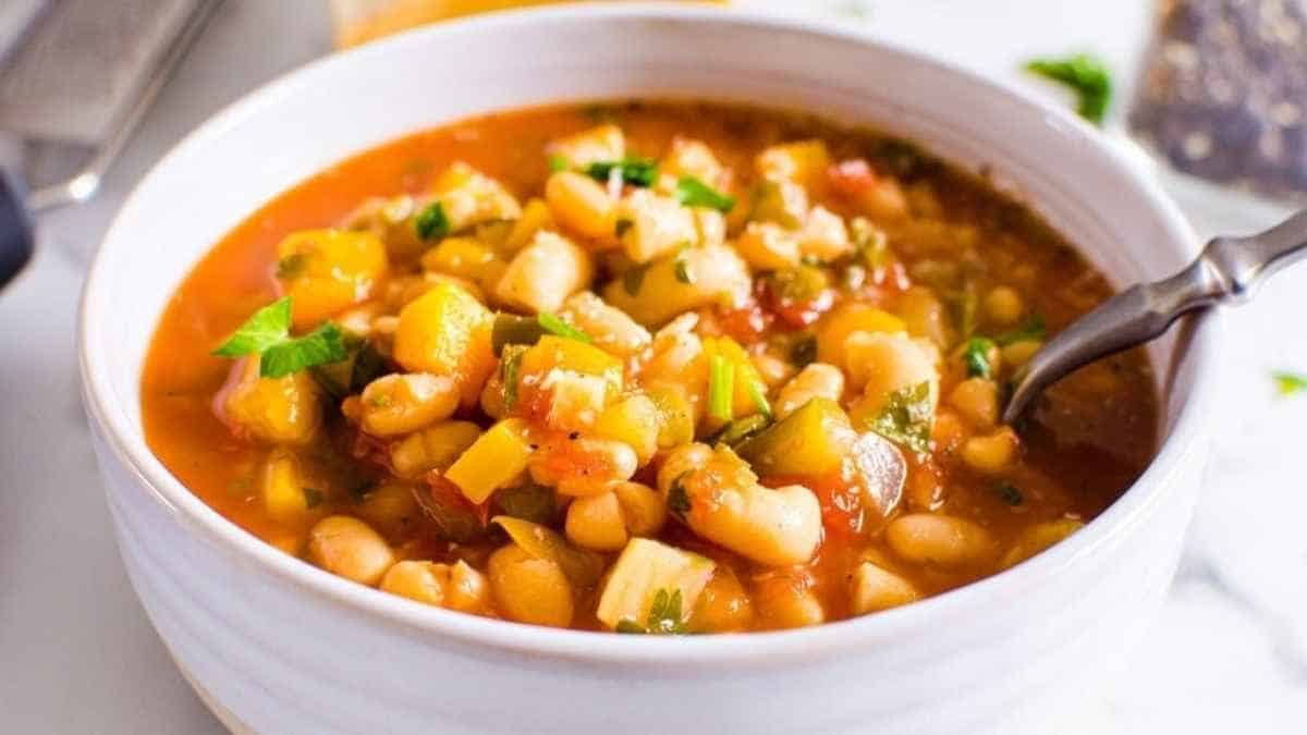 White bean and vegetable soup in a white bowl.