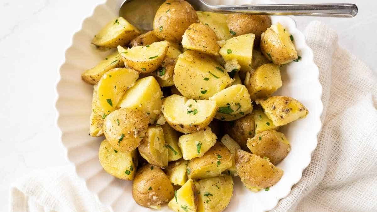Potatoes in a white bowl with a spoon.