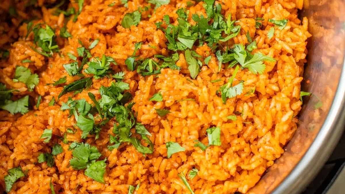A bowl of orange rice with cilantro on top.