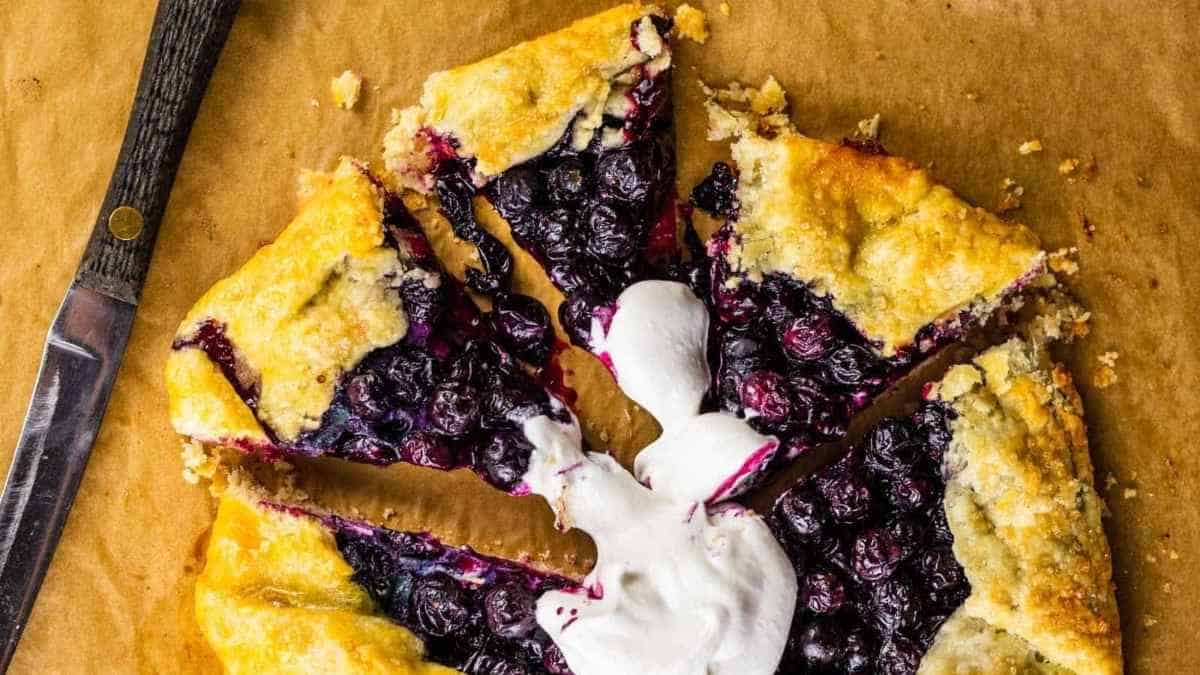 A blueberry galette with whipped cream and blueberries.