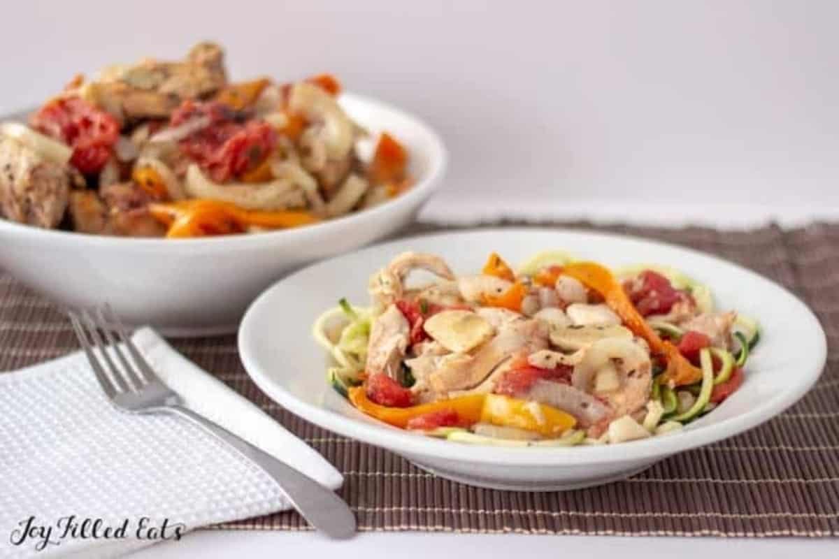 Two bowls of chicken and vegetables on a table.