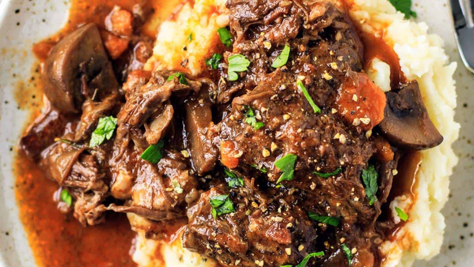 A plate of beef stew with mashed potatoes and gravy.