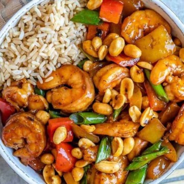 A bowl of stir fried shrimp with peanuts and vegetables.