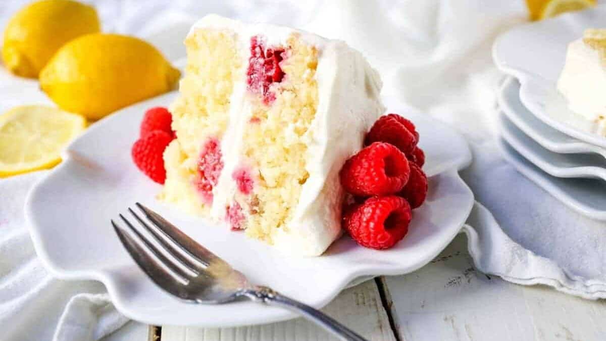 A slice of lemon cake on a plate with raspberries.