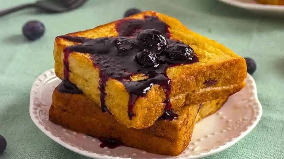 A stack of french toast with blueberry sauce on a plate.