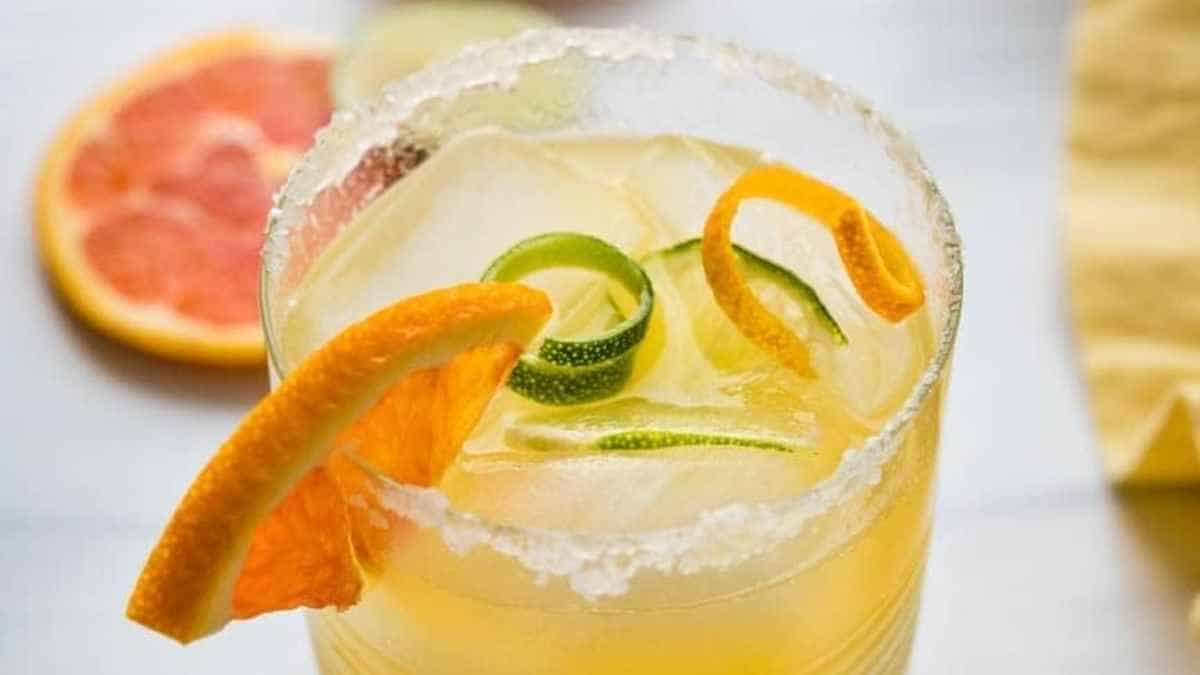 A margarita with orange slices and lime wedges.