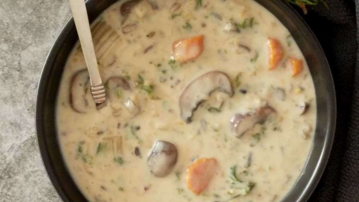 Mushroom soup in a black bowl with a spoon.