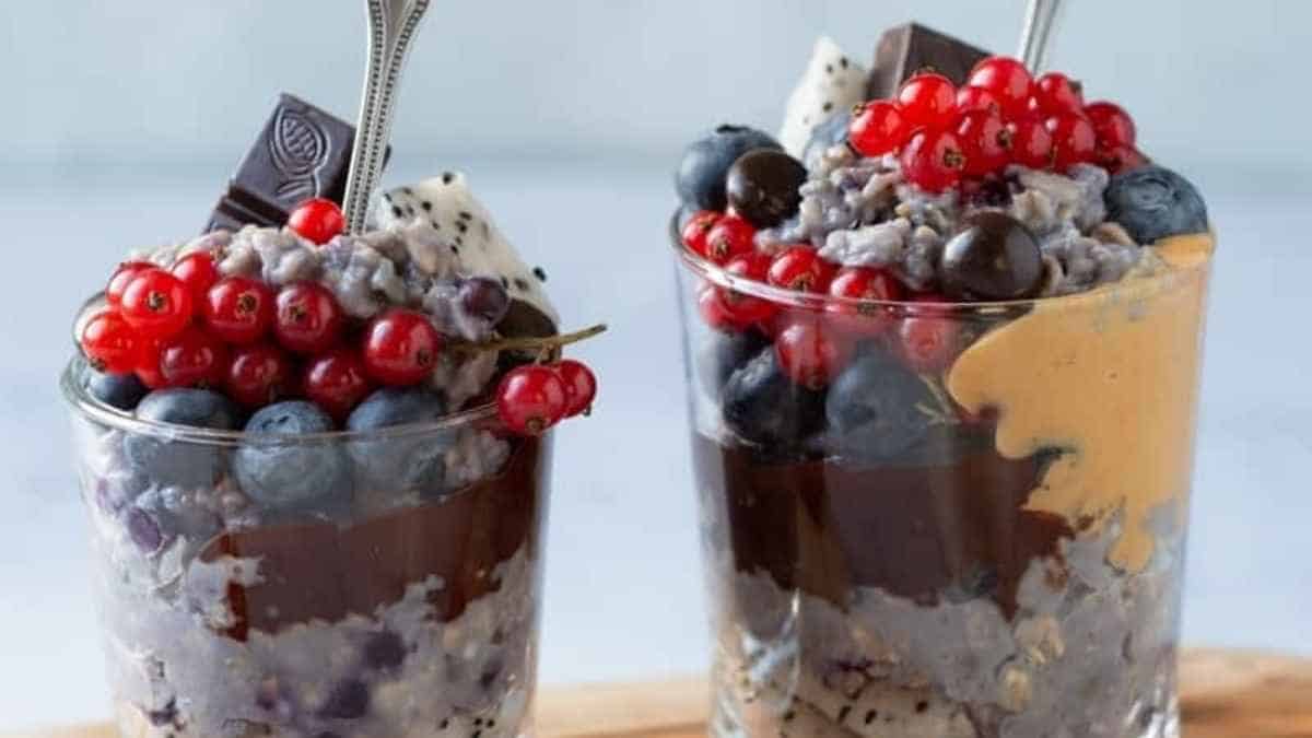 Two glasses filled with chocolate pudding and berries.