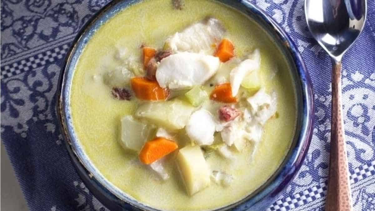 A bowl of soup with carrots and potatoes.