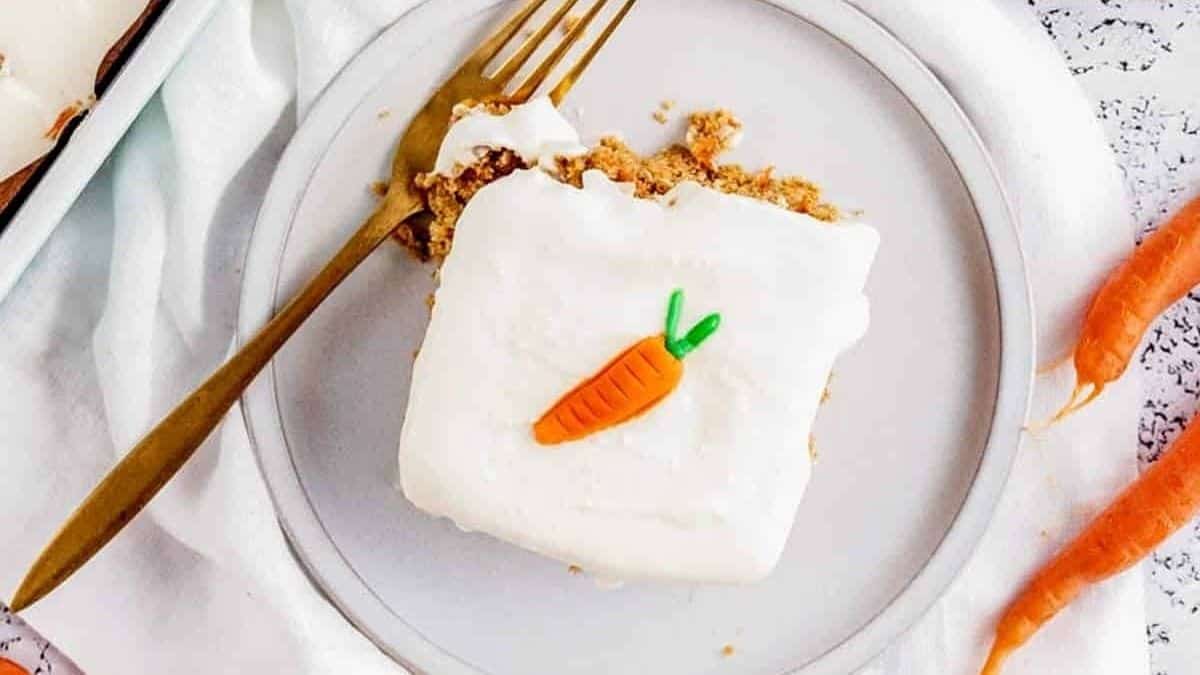 A slice of carrot cake on a plate with a fork.