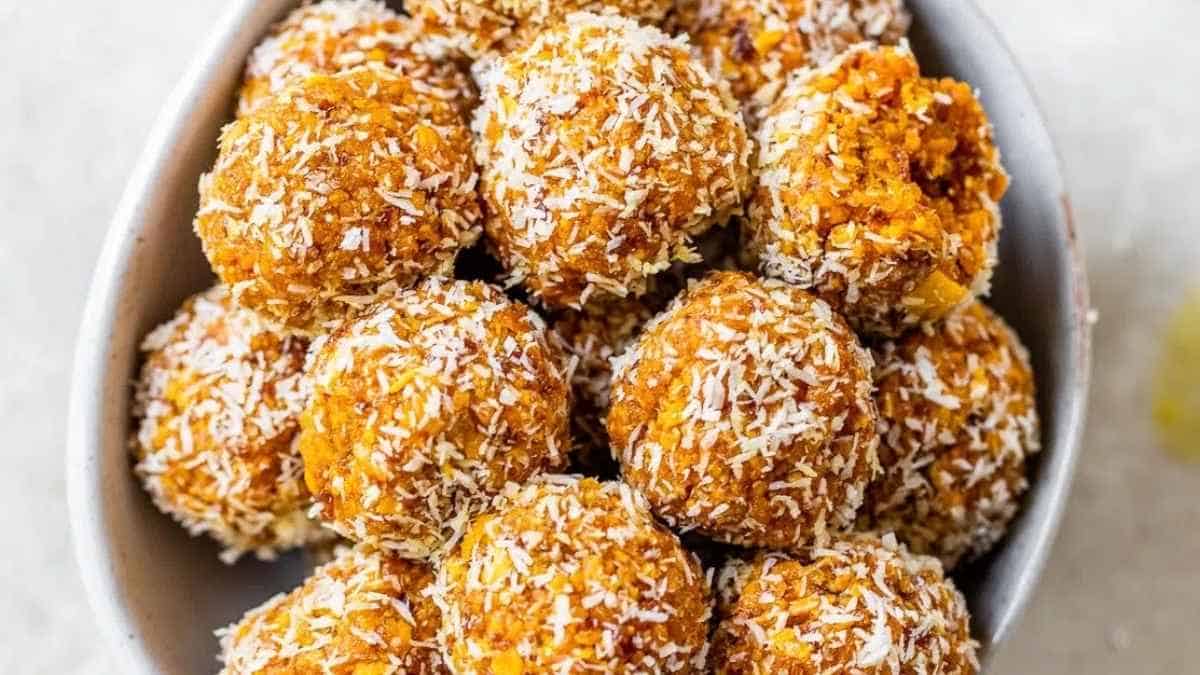 A bowl full of coconut balls on a white table.