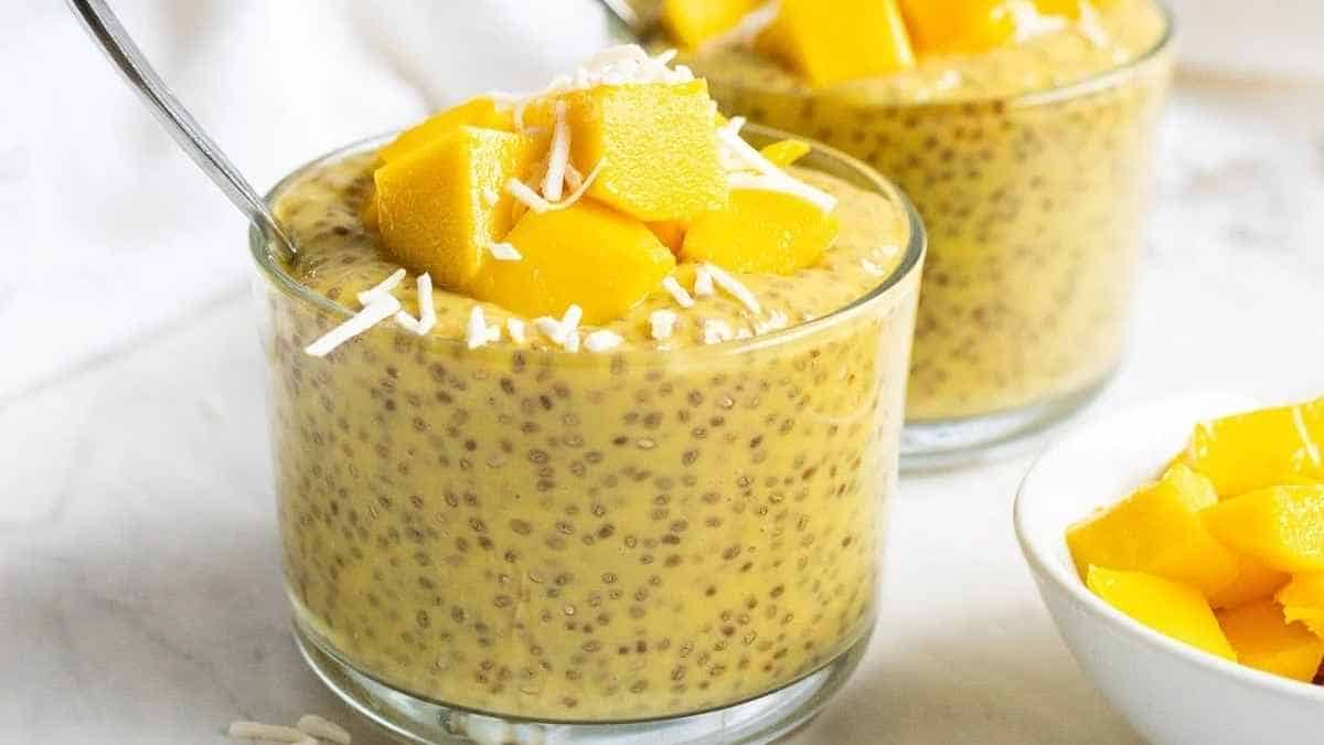 Two glasses of mango chia pudding with a spoon.