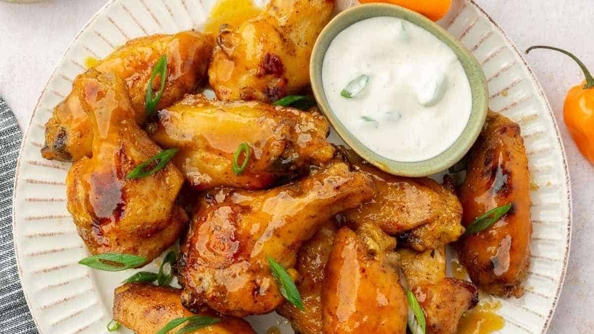 A plate with chicken wings and dipping sauce.