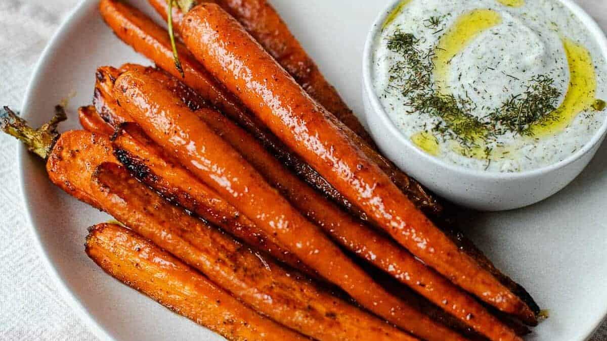 Roasted carrots with a dip on a plate.