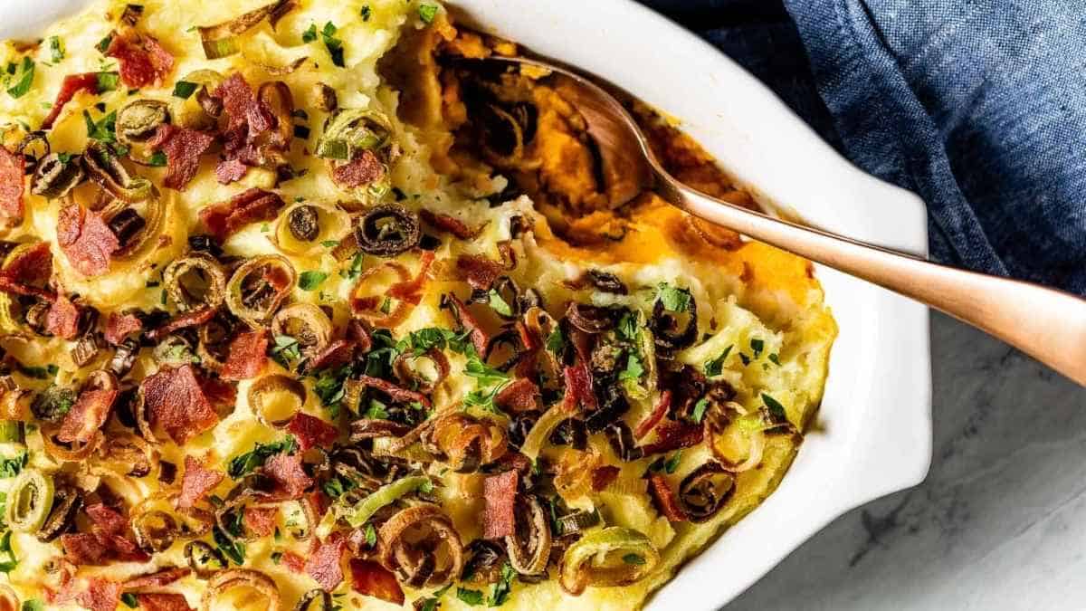 Sweet potato casserole with bacon and onions in a white dish.
