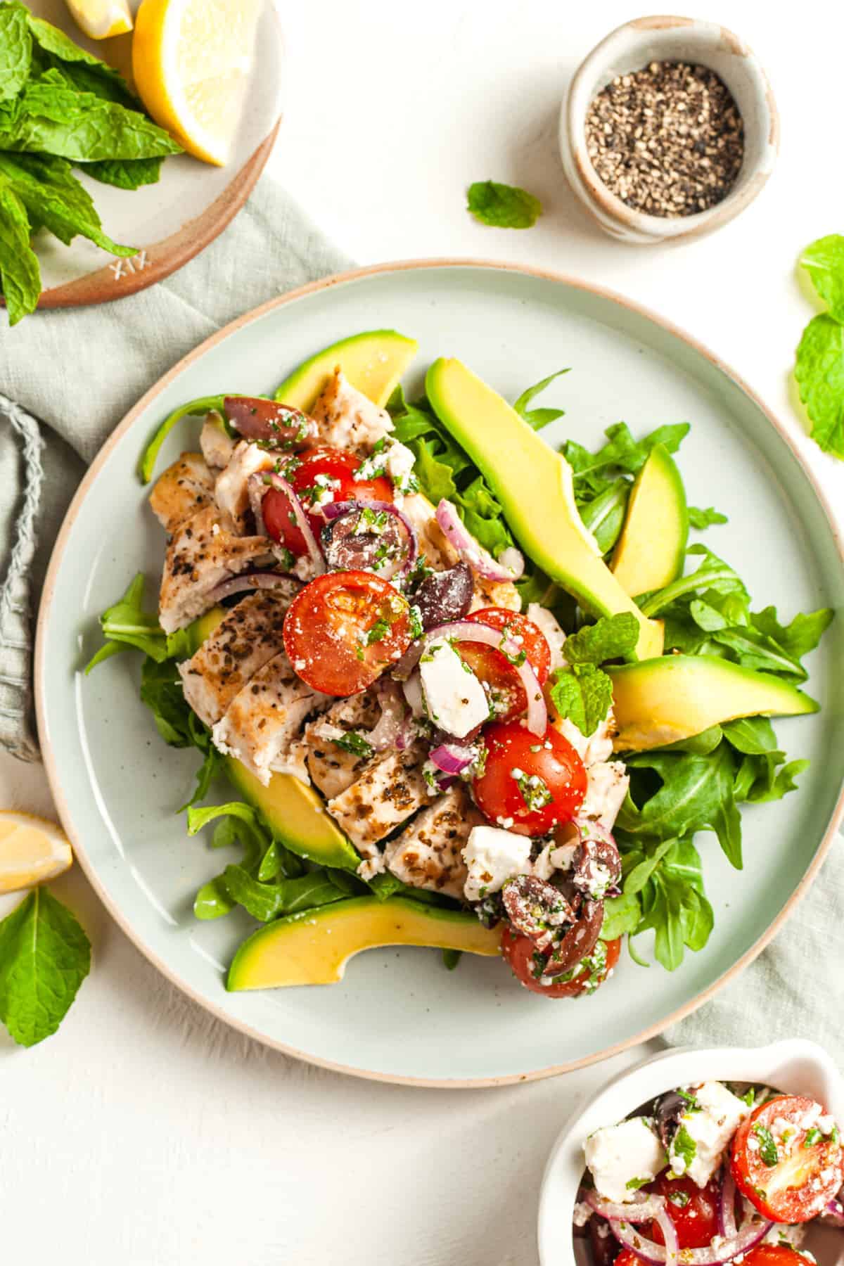 A plate of chicken salad with tomatoes, cucumbers and feta cheese.