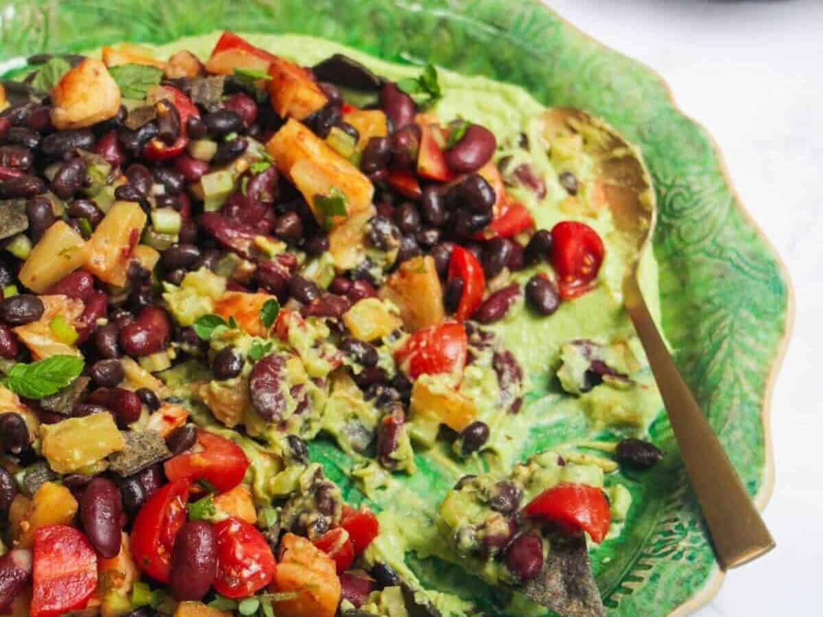A green plate with a black bean and black olive hummus.