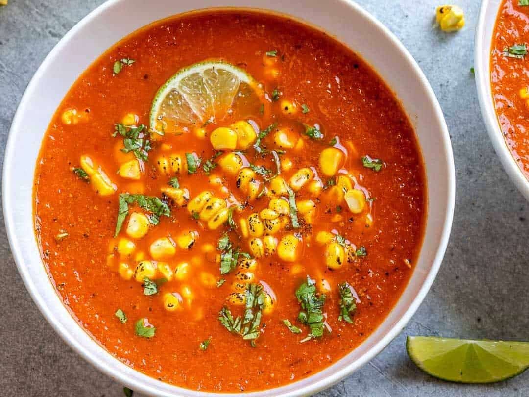 Two bowls of mexican corn soup with lime and corn.