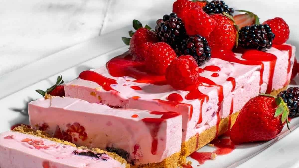 A slice of cake with berries and blackberries on top.