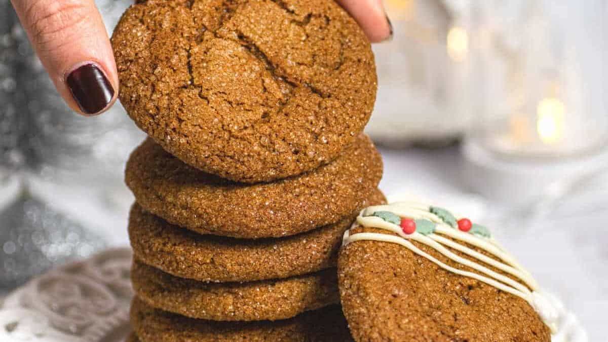 A person holding a stack of ginger cookies on a plate.