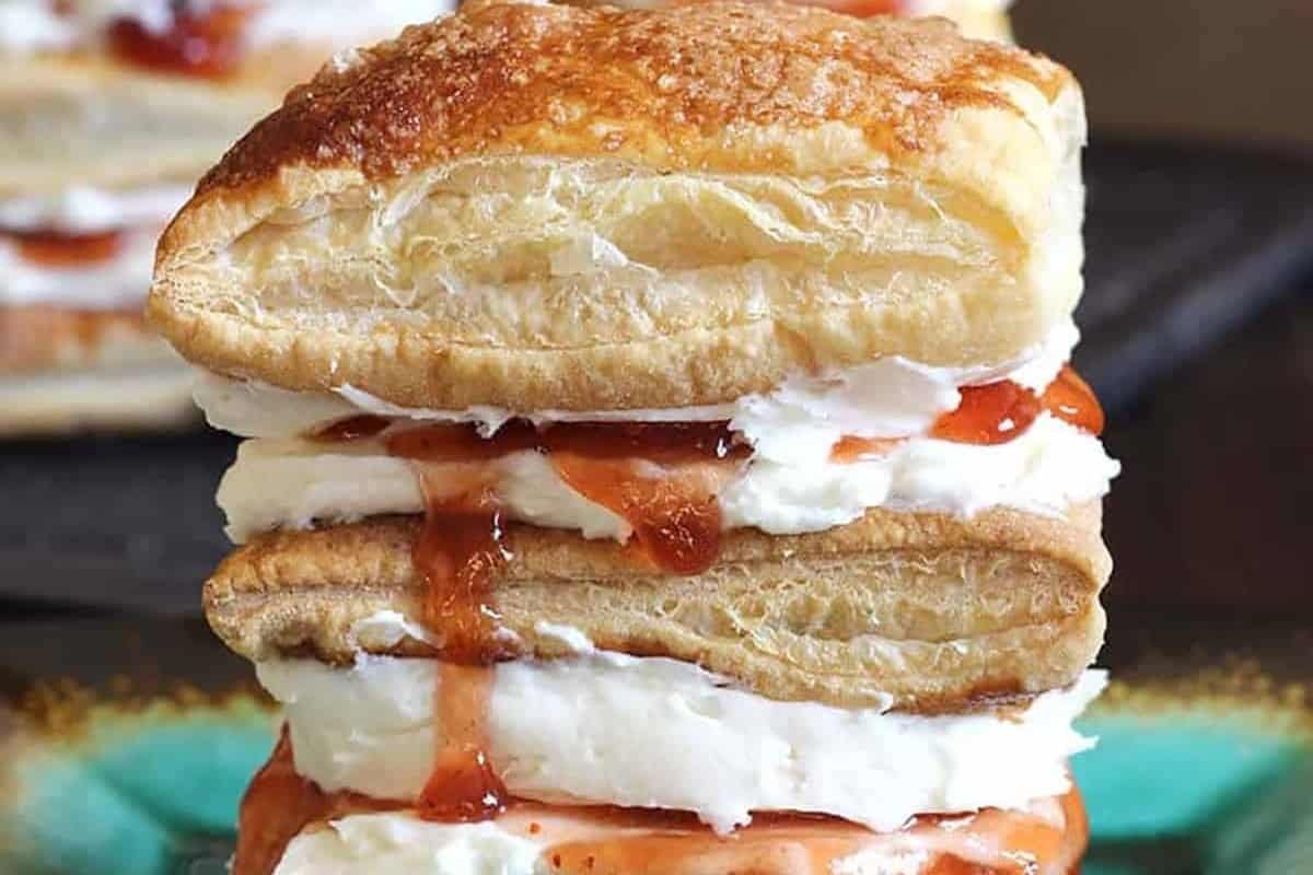 A stack of pastries topped with cream and jam.