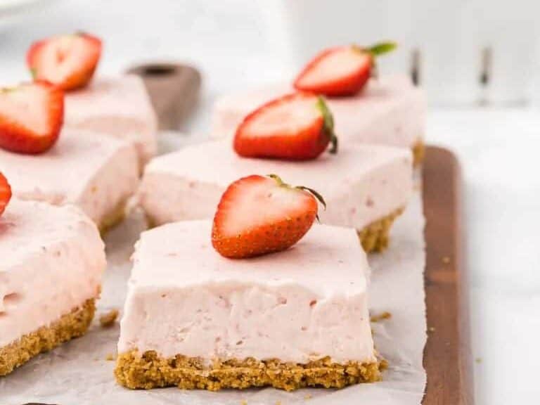 Strawberry cheesecake bars on a cutting board.