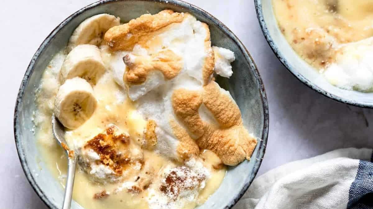 Three bowls of dessert with whipped cream and bananas.