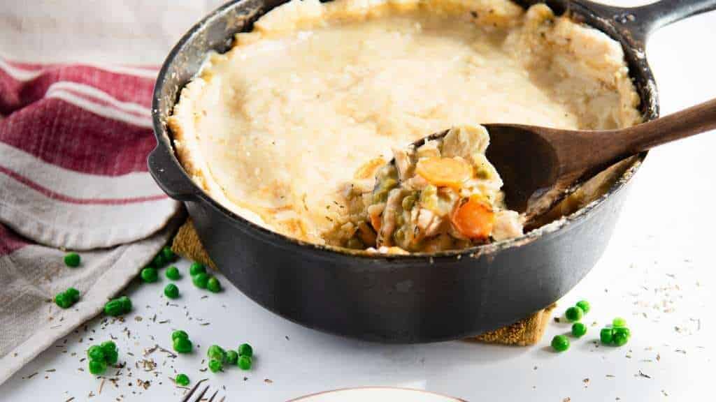 Chicken pot pie in a skillet with a wooden spoon.