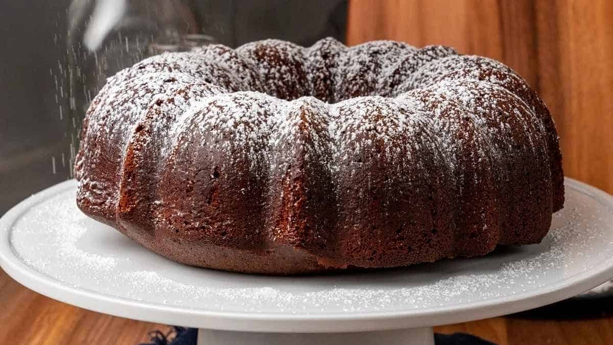 A bundt cake on a white plate with powdered sugar.