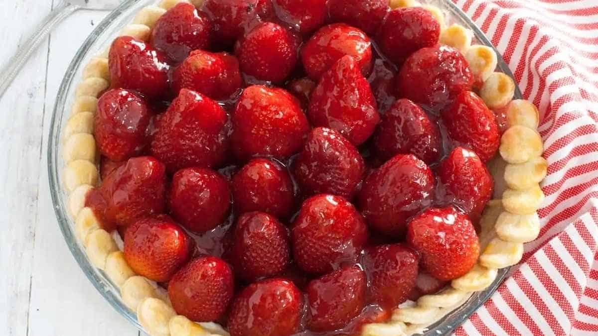 Strawberry pie in a glass dish with a fork.