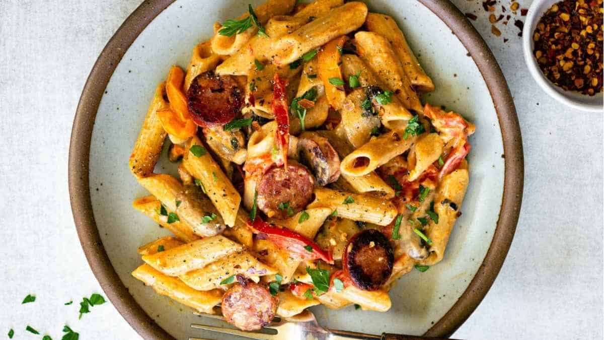 A plate of pasta with sausage and peppers.
