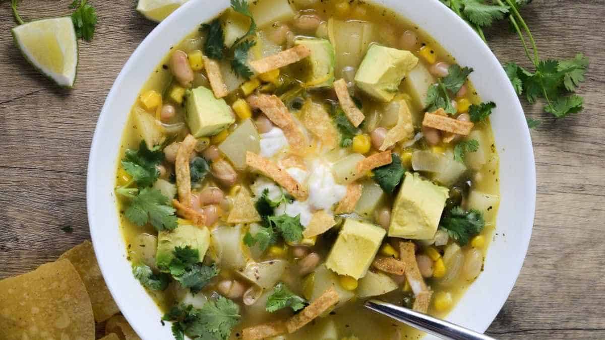 A bowl of mexican vegetable soup with tortilla chips.