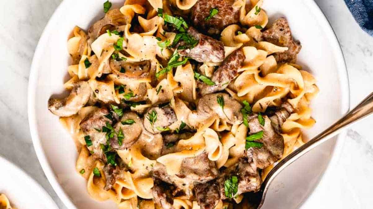 Beef stroganoff in a white bowl with a fork.