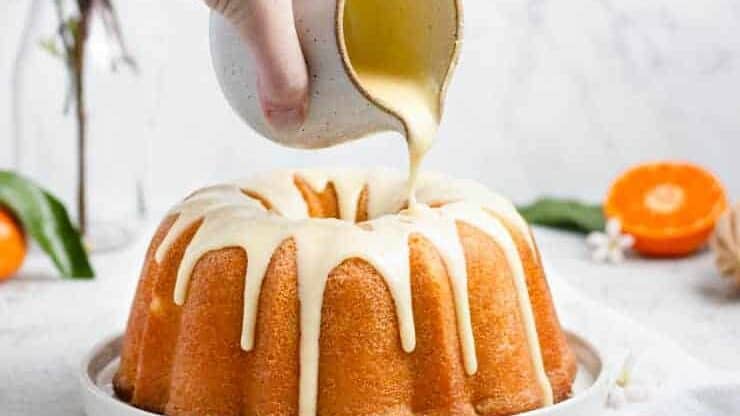 A person pouring icing onto a bundt cake.