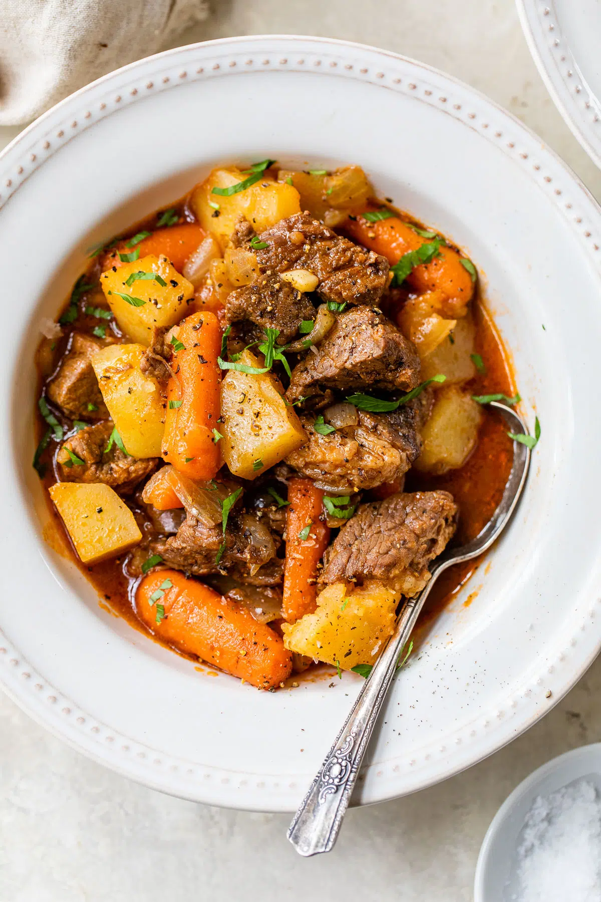 Chuck steak recipes: Delicious beef stew made with tender pieces of chuck steak, accompanied by hearty potatoes and vibrant carrots, presented impeccably in a white bowl.