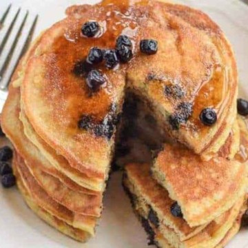 A stack of pancakes with blueberries on top.
