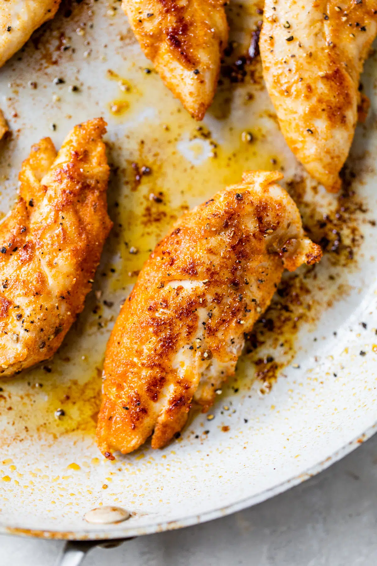 Chicken breasts cooked in a pan, bursting with sensational flavors, against a pristine white background.