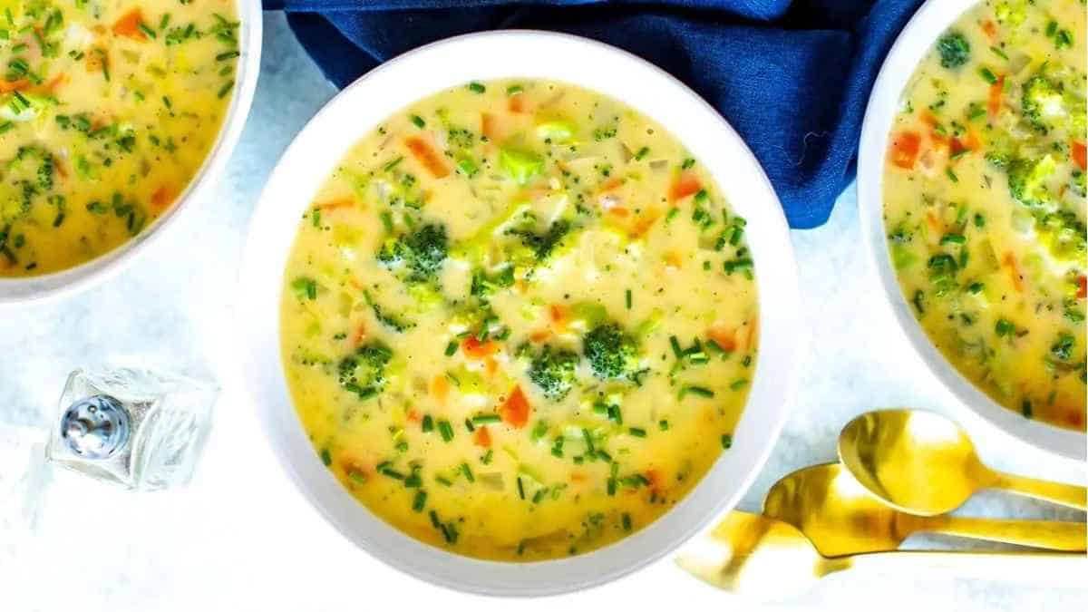 Three bowls of soup with broccoli and carrots.