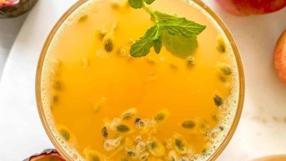A glass of orange juice with pomegranate and mint leaves.