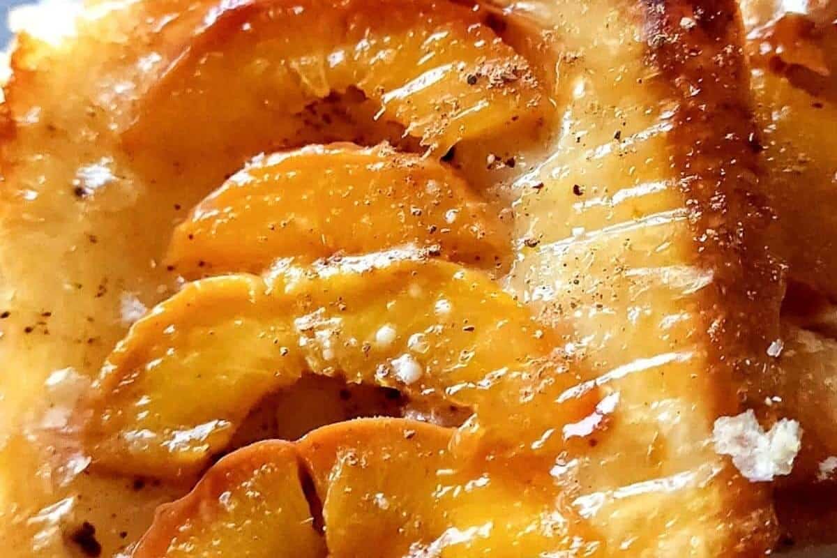 A close up of a slice of bread with peaches on it.