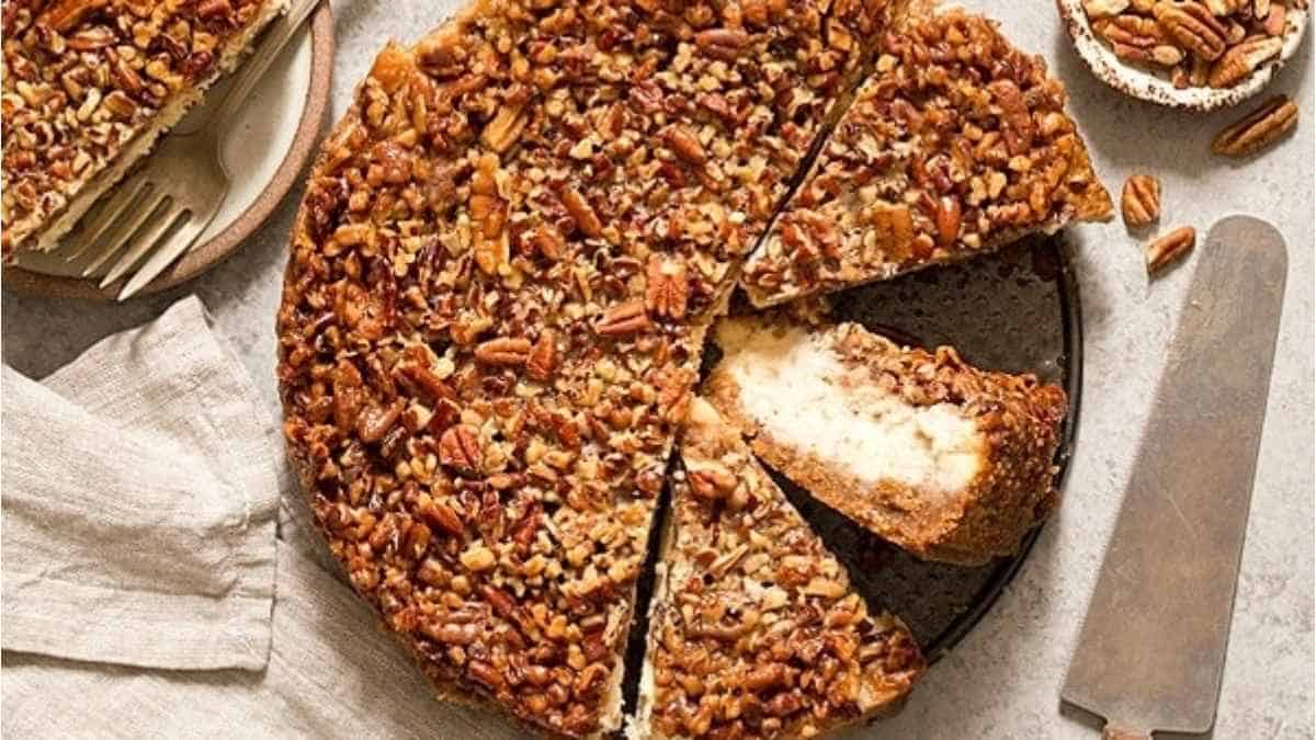 Pecan cheesecake on a plate with a slice taken out.